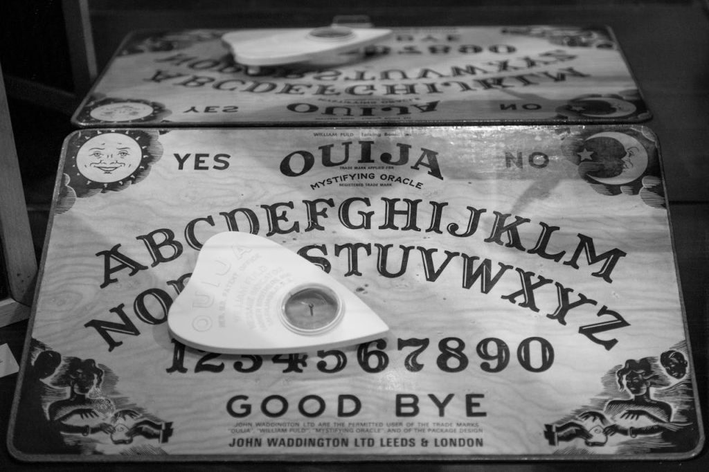 Monochrome image of a vintage Ouija board and planchette, evoking mystery.